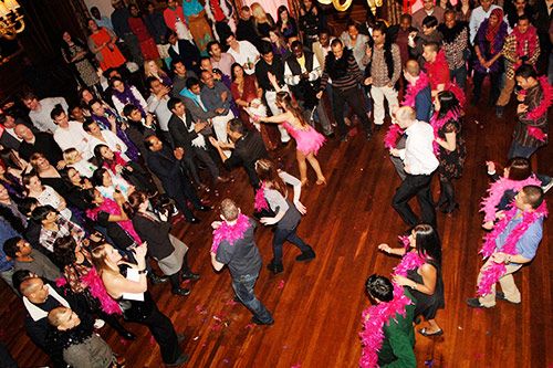 Costumed salsa performers dancing for a crowd on a wooden dance floor.